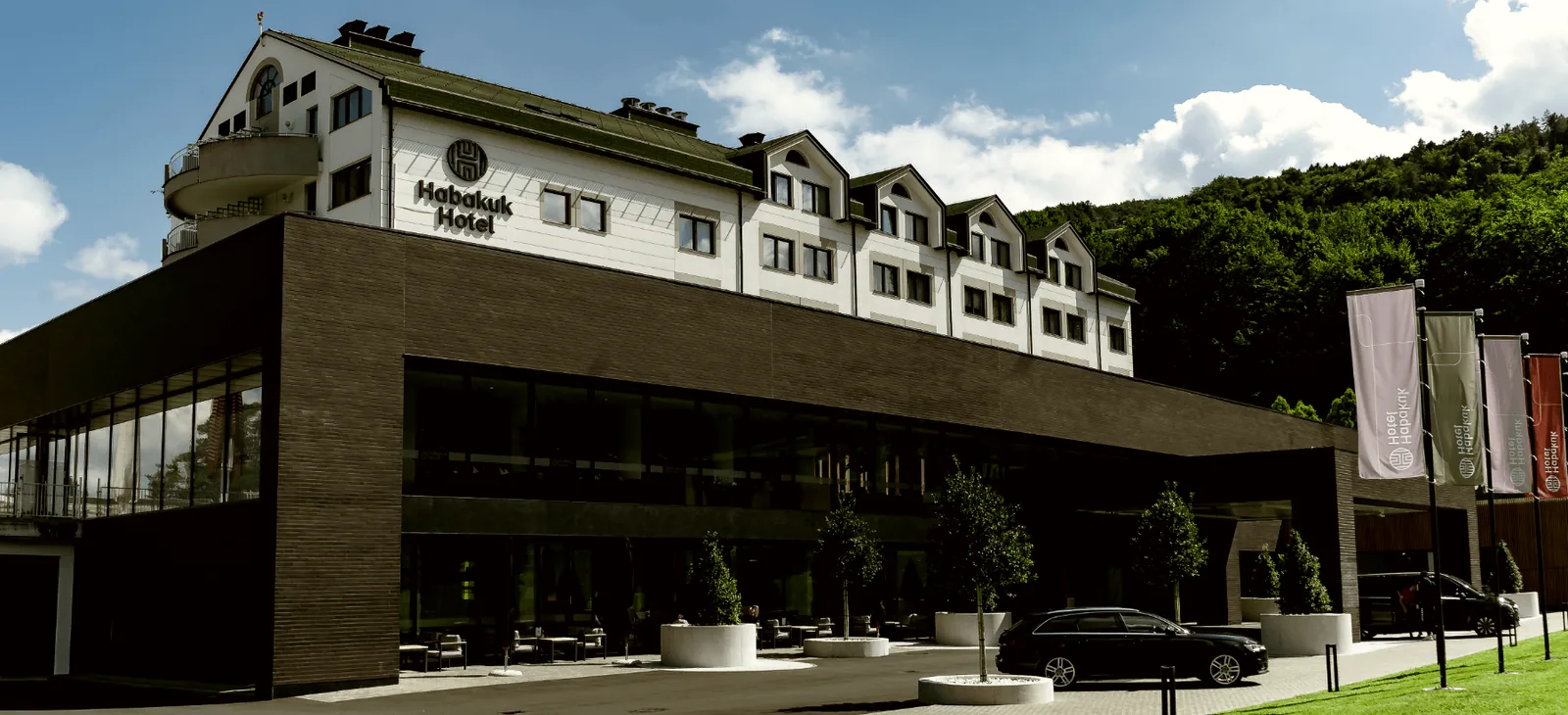 Hotel Habakuk z napisom na pročelju in pohorskim gozdom v ozadju